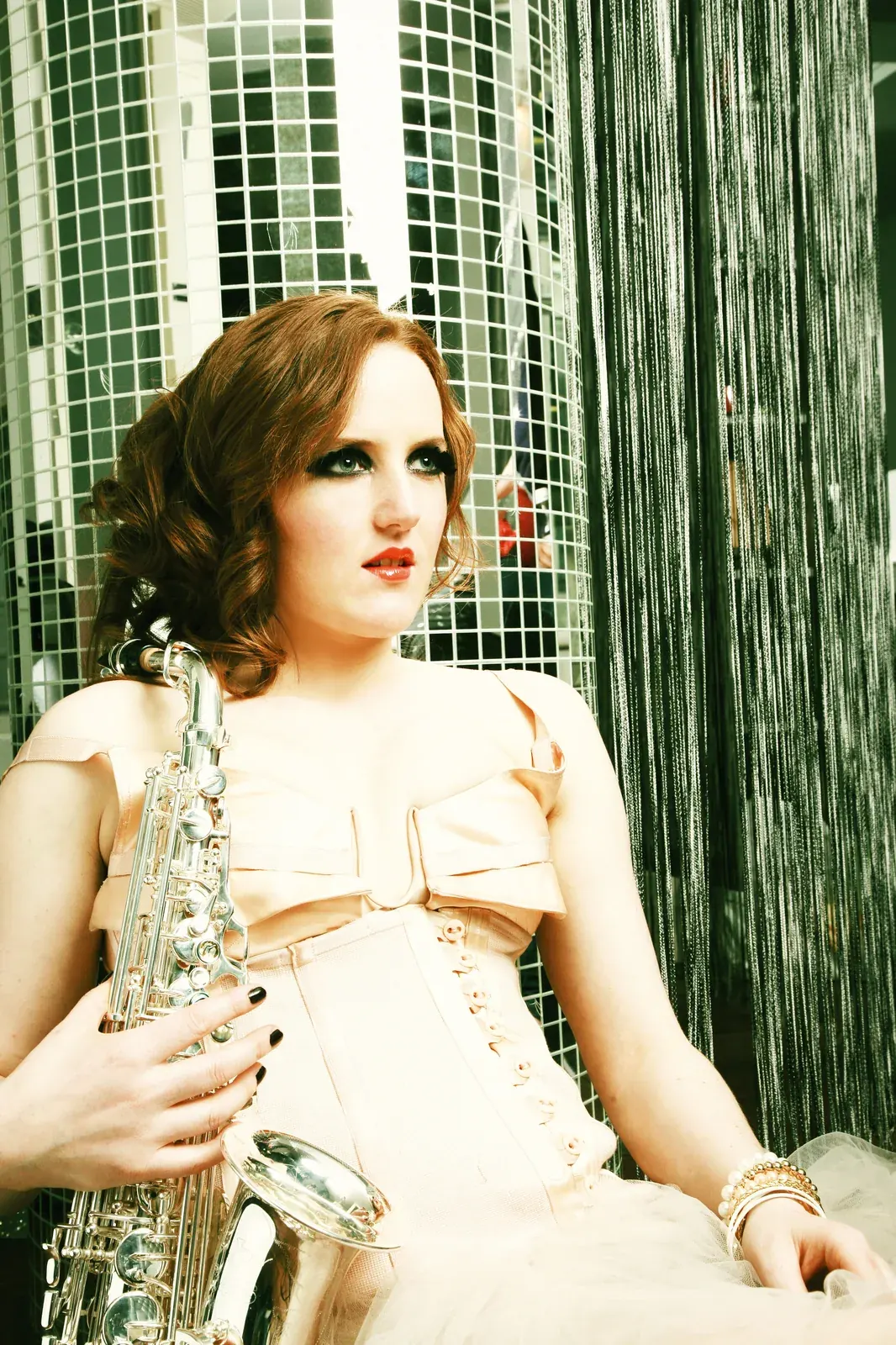 Sarah Saxophone portrait against a padded headboard