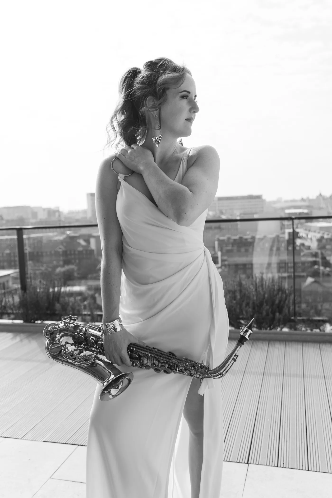 Sarah Saxophone in a white gown holding her saxophone on a rooftop terrace
